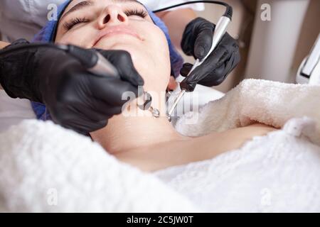 The beautician performs the microcurrent procedure in the beauty salon. The procedure stimulates collagen production, lifting, fights wrinkles, facial Stock Photo