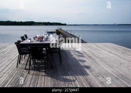 Table and chairs at the pier with the sea in the background. Table set for coffee break with fresh strawberries on a summer day in Karlskrona, Sweden Stock Photo