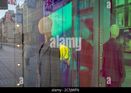 With a further 184 reported UK Covid deaths in the last 24 hrs, a total now of 43,414, retail mannequins in the window of the Armani store on New Bond Street are seen with, in the background, Union Jack flags and the thank you banners that support NHS key workers during the Covid pandemic lockdown, now easing after three months of the Stay At Home policy but now being relaxed as the shops re-open, on 26th June 2020, in London, England. Government restrictions on the 2 metre rule is to be realxed on 4th July and replaced with 'one metre plus' in the hope it stimulates the struggling UK economy. Stock Photo