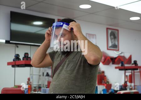 Sidcup, Kent, UK. 03rd July, 2020. A partner in Red Barber Shop in Sidcup High Street tries a face shield as they prepare to reopen after covid 19 lockdown rules are relaxed by the government. Sidcup, Kent on 3 July 2020. Photo by Alan Stanford. Credit: PRiME Media Images/Alamy Live News Stock Photo