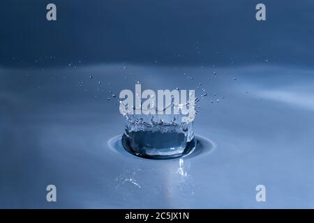 Splashing water drop hitting water surface Stock Photo