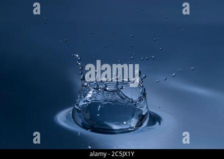 Splashing water drop hitting water surface Stock Photo