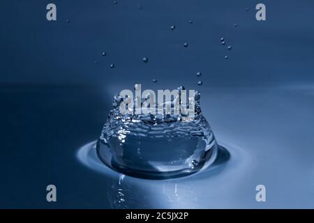 Splashing water drop hitting water surface Stock Photo