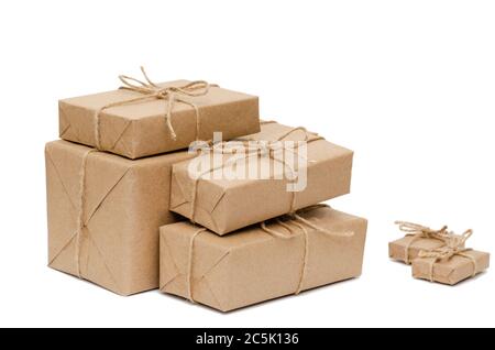 Pile of stacked boxes wrapped with brown kraft paper and tied with twine on a white background. Delivery, moving, package and gifts concept. Closeup Stock Photo