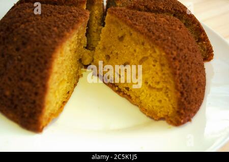 Sliced, divided sponge pie into portions on a white background close up. One piece is taken away Stock Photo