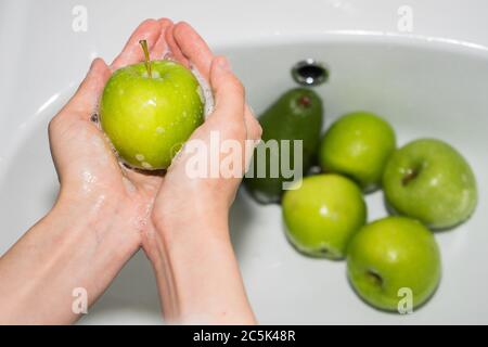 Washing fruit. Hands and soapy green apple Stock Photo