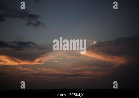 Sunset or sunrise sky. Dense clouds backlit by pink sunlight in the evening or morning sky Stock Photo