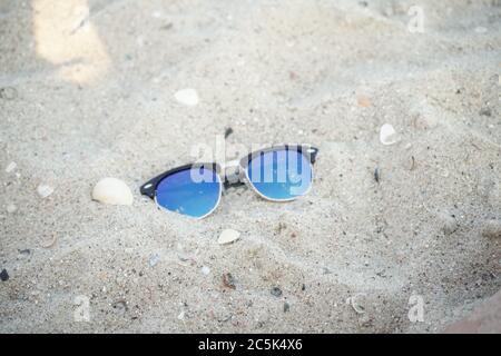 Seaside with shells in the foreground and sunglasses on a sandy beach on a blurred background Stock Photo