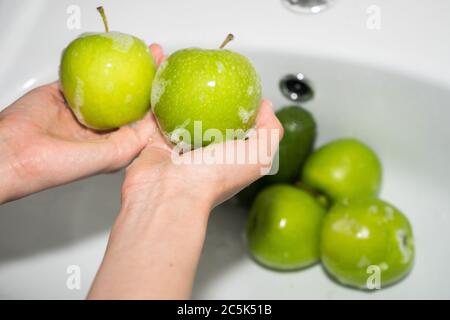 Washing fruit. Hands and soapy green apple Stock Photo