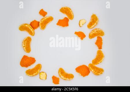 A frame from peel's tangerines and mandarin pieces on white background. A composition of the mandarin pieces and peel. Stock Photo