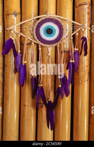 divine eye of providence dreamcatcher with colored feathers on a wodden background. Stock Photo