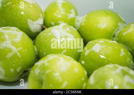 Washing fruit. Soapy green apples in the sink.  Stock Photo