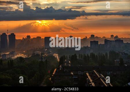 The sun's rays break through the rain clouds of a cloud at dawn and illuminate a sleeping city.