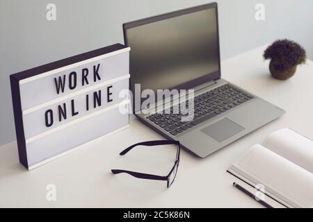 Online work concept. Workplace with laptop glasses notebook and books on the table. Stock Photo