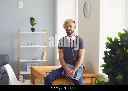 Handsome guy with notebooks and headphones sitting on table at home office. Online education, work, communication Stock Photo