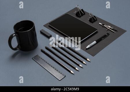 Flat lay of blank black paper sheet, black stationery items and coffee cup on gray desktop. Mock up Stock Photo