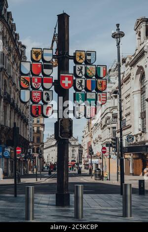 London, UK - June 13, 2020: Flag pole displaying the 26 regional Swiss flags in Leicester Square, London, one of the most popular tourist sites in the Stock Photo