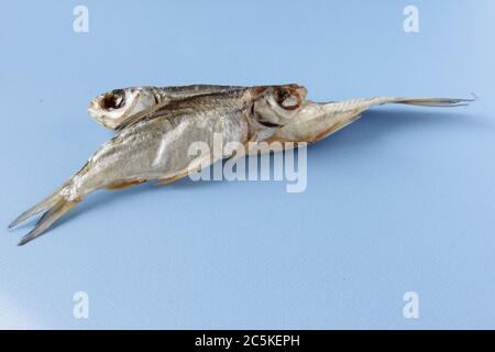 Two dried fish on blue background. Two salty dry river fish on a light blue background. Top view. Copy space. Stock Photo