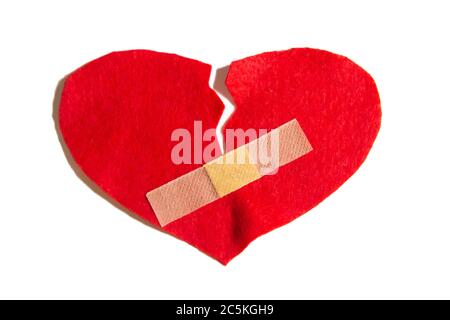 Broken heart and glued together with a band-aid. A heart from felt. A concept about broken love. Heart with plaster isolated on white background Stock Photo