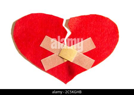 Broken heart and glued together with a band-aid. A heart from felt. A concept about broken love. Heart with plaster isolated on white background Stock Photo