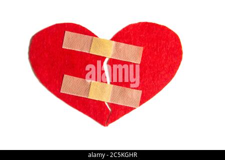 Broken heart and glued together with a band-aid. A heart from felt. A concept about broken love. Heart with plaster isolated on white background Stock Photo