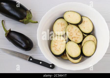 Eggplant, sliced with slices, are in bowl on a white background, top view, Closeup Stock Photo
