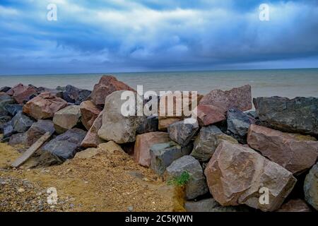 2 The rocky barrier protecting the sandy cliffs on a stormy day on Happisburgh beach, North Norfolk coast Stock Photo