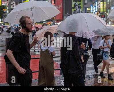 Male tourist with umbrella at Shibuya crossing, Tokyo, Japan during a ...