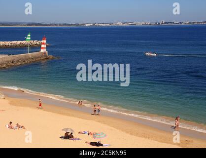 Lagos, Algarve, Portugal. Cliff top view of tourists sunbathing in the warm sunshine on the city beach in Lagos, in the Western Algarve. Stock Photo