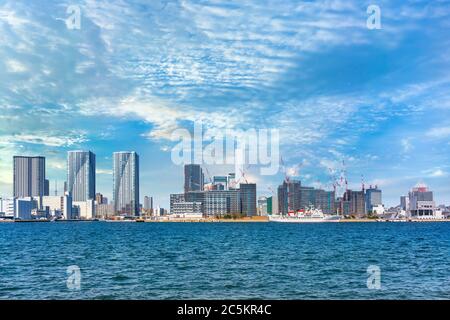 tokyo, japan - march 01 2020: Panoramic seascape of a ship moored on Tokyo Bay with buildings of Tokyo 2021 Olympic Village Plaza under construction i Stock Photo