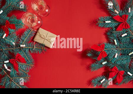 Two glasses of champagne with Christmas tree branch and small gift on a red background Stock Photo