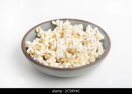 Popcorn in a ceramic bowl set on a plain white background. Stock Photo