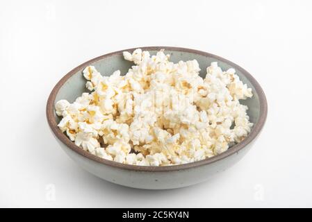 Popcorn in a ceramic bowl set on a plain white background. Stock Photo