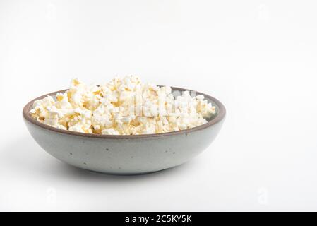 Popcorn in a ceramic bowl set on a plain white background. Stock Photo