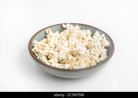 Popcorn in a ceramic bowl set on a plain white background. Stock Photo