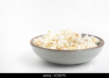 Popcorn in a ceramic bowl set on a plain white background. Stock Photo