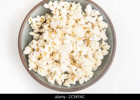 Popcorn in a ceramic bowl set on a plain white background. Stock Photo
