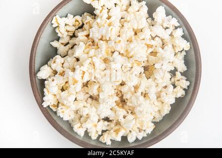 Popcorn in a ceramic bowl set on a plain white background. Stock Photo