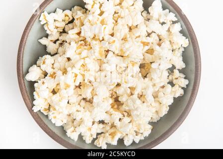 Popcorn in a ceramic bowl set on a plain white background. Stock Photo
