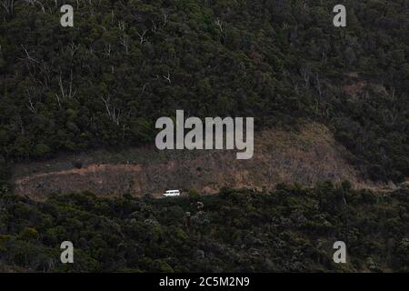 White mini van traveling alongside cliff edge Great Ocean Road, Victoria, Australia. Stock Photo