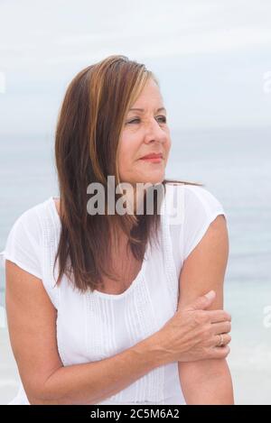 Portrait attractive mature woman alone outdoor, with sad and concerned facial expression, with blurred background. Stock Photo