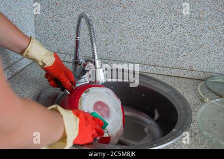 cropped view of woman hands in rubber gloves cleaning dirty pan with sponge Stock Photo