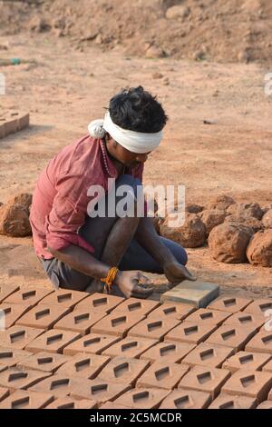 TIKAMGARH, MADHYA PRADESH, INDIA - FEBRUARY 07, 2020: Unidentified Indian man making house bricks by hand using a mold and wet clay. Stock Photo