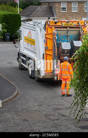 A recycling collector, in high visibility orange clothing, inspects black wheelie bins as they empty non-recyclable rubbish into a lorry. Stock Photo