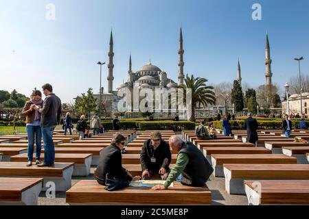 Tourists relax on seats in front of the magnificent Blue Mosque (Sultan Ahmet Camii) in the Sultanahmet district of Istanbul in Turkey. Stock Photo