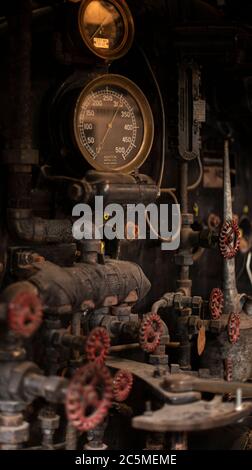 Rusty old valves, gauges and metal parts on an antique steam locomotive ...