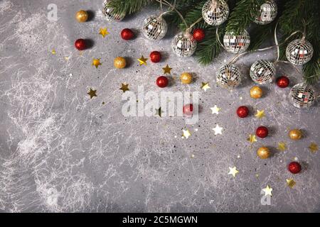 Christmas fir branch with decorative garlands balls glowing light on grey background with golden and red balls and stars Stock Photo