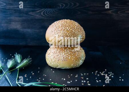 Two buns  with sesame seeds on the wood background. Stock Photo
