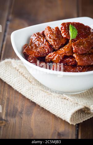Sun dried tomatoes with basil in white bowl Stock Photo
