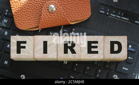 Fired word on the wooden cubes on computer keyboard and brown wallet. Labourforce cut unemployed concept ofr business crisis and career Stock Photo